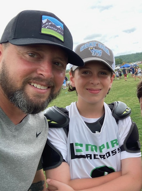 Philip Mascolo with a youth lacrosse player on a field